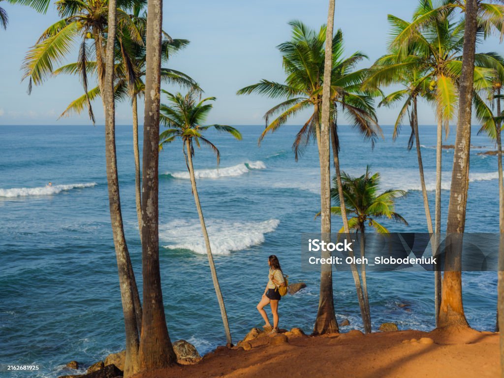 Cheerful woman  looking at ocean standing among  palm trees grove